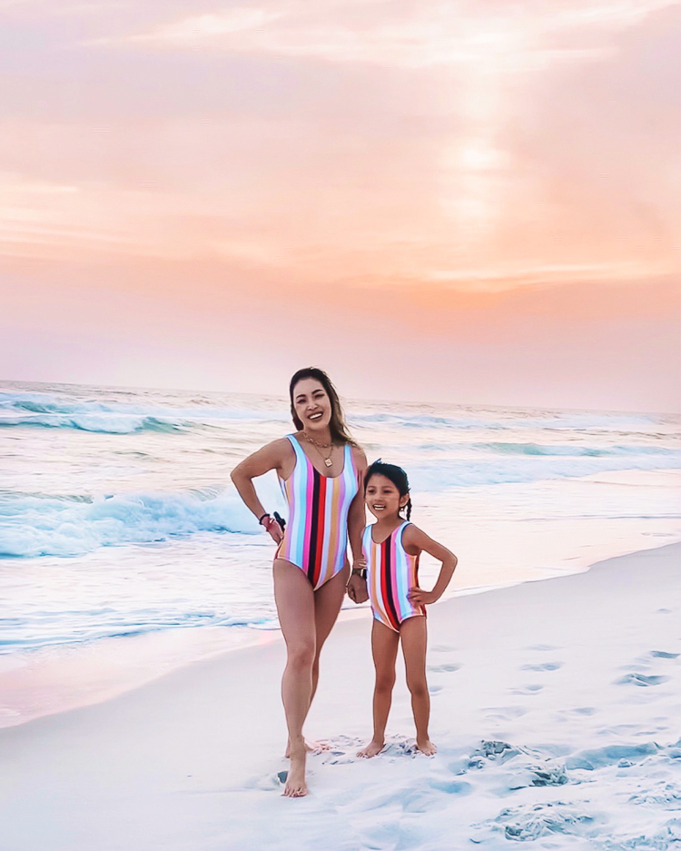 cute & little | dallas mom family travel blog | panama city beach 30a destin florida travel guide kids |Panama City Beach by popular Dallas travel blog, Cute and Little: image of a mom and daughter standing on a white sand beach and wearing matching multi color stripe swimsuits. 