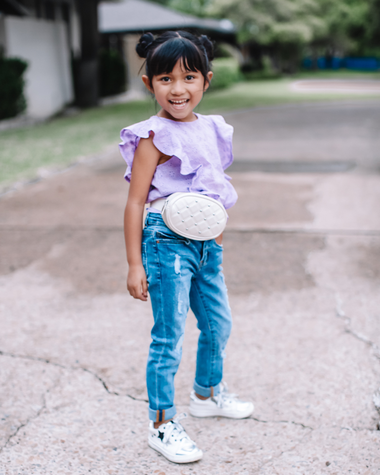 cute & little | dallas mom family blog | kidpik review | best kids style box |KidPik Box by popular Dallas petite fashion blog, Cute and Little: image of a young standing outside and wearing a purple eyelet flutter sleeve shirt, distressed jeans, silver sneakers, and studded white belt bag.
