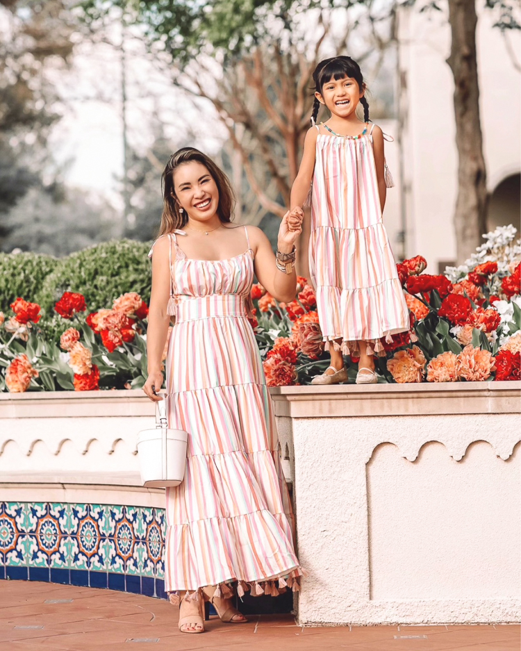 cute & little | dallas mom petite fashion blog | chicwish matching mom daughter dresses mothers day easter beach vacation photoshoot outfit |Mommy and Me Dresses by popular Dallas petite fashion blog, Cute and Little: image of a mom and daughter standing next to each other and wearing Chicwish Rainbow Candy maxi dresses and holding a Kate Spade Cameron bucket bag. 