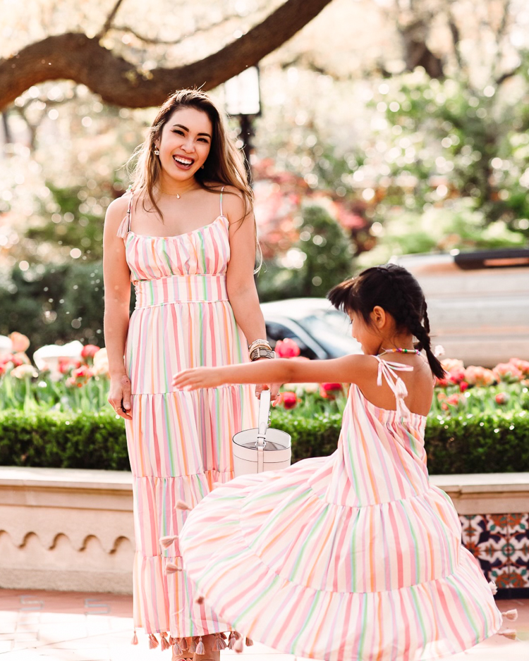 cute & little | dallas mom petite fashion blog | chicwish matching mom daughter dresses mothers day easter beach vacation photoshoot outfit |Mommy and Me Dresses by popular Dallas petite fashion blog, Cute and Little: image of a mom and daughter standing next to each other and wearing Chicwish Rainbow Candy maxi dresses and holding a Kate Spade Cameron bucket bag. 