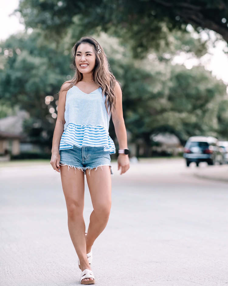 cute & little | dallas mom petite fashion blog | amaryllis stripe peplum top, abercrombie mom shorts | memorial day weekend 2021 sales | Memorial Day Sales by popular Dallas lifestyle blog, Cute and Little: image of a woman walking down a street and wearing a blue and white stripe tank, cut off denim shorts, and white slide sandals. 