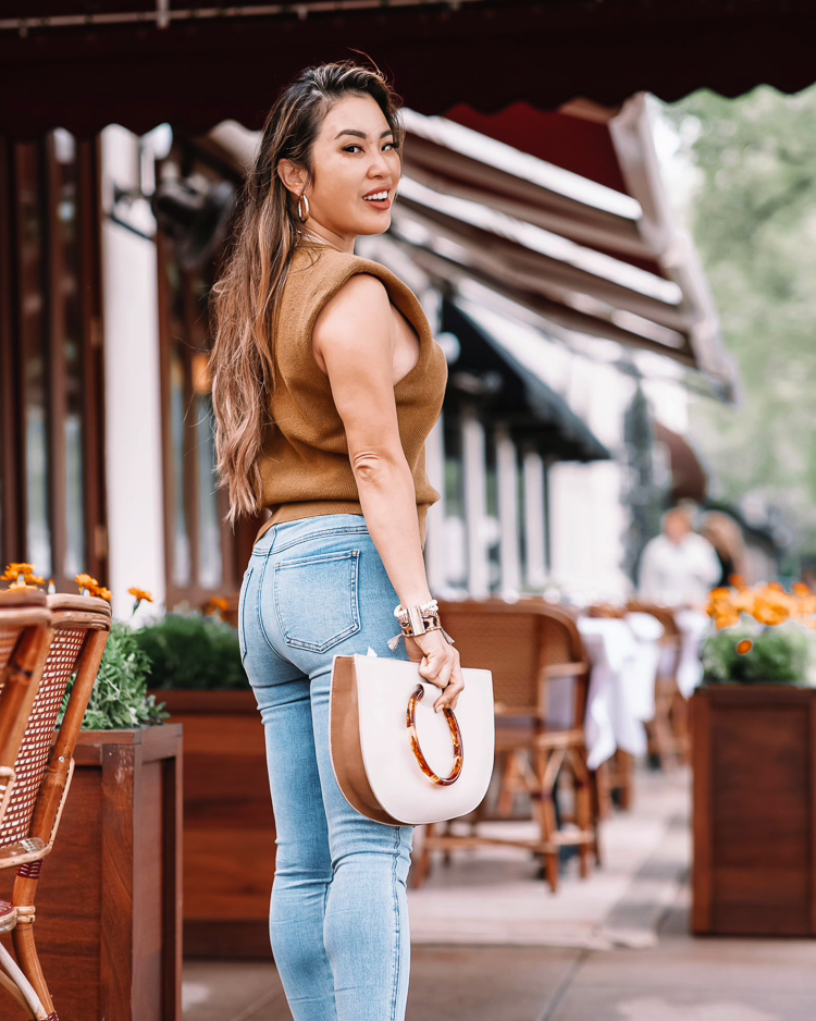 cute & little | dallas petite fashion blog | spanx denim jeans review | Spanx Jeans by popular petite Dallas fashion blog, Cute and Little: image of a woman waling down a street and wearing a brown sleeveless shirt, Spanx jeans, Gucci belt and braided strap sandals. 