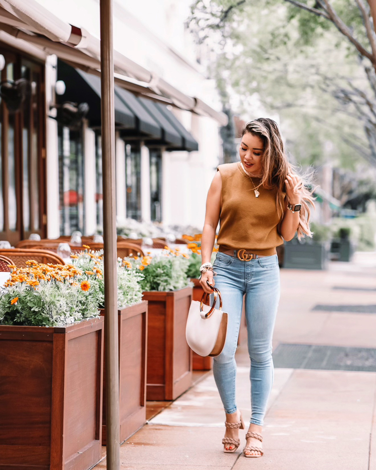 cute & little | dallas petite fashion blog | spanx denim jeans review | Spanx Jeans by popular petite Dallas fashion blog, Cute and Little: image of a woman waling down a street and wearing a brown sleeveless shirt, Spanx jeans, Gucci belt and braided strap sandals. 