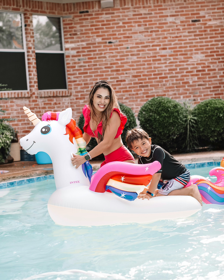 cute & little | dallas mom family travel blog | walmart plus review | backyard pool day must-haves | Pool Day by popular Dallas lifestyle blog, Cute and Little: image of a woman wearing a red bikini and sitting in a unicorn pool float in a swimming pool with her young son. 