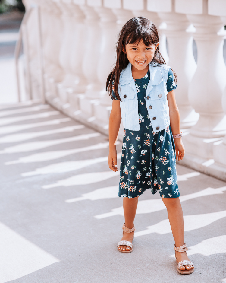 cute & little | dallas petite fashion blog | back to school outfits jcpenney |  School Routine by popular Dallas motherhood blog, Cute and Little: image of a young girl standing outside and wearing a floral print dress, gold strap sandals, and denim dress. 
