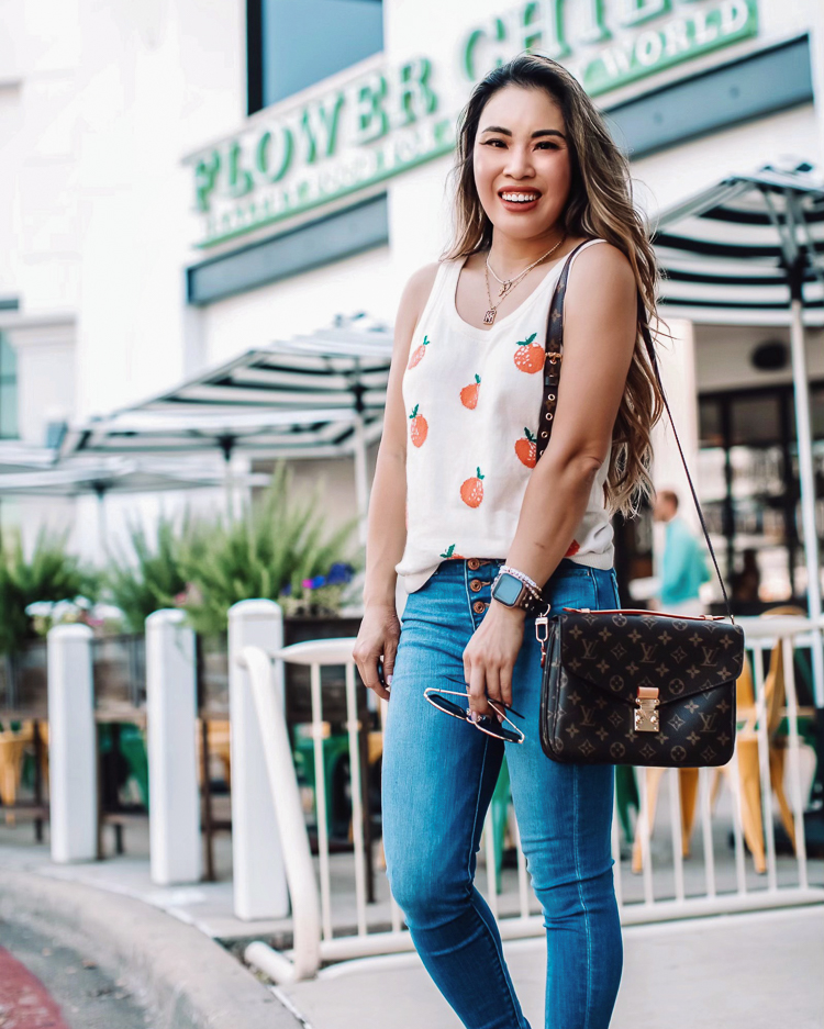 cute & little | dallas petite fashion blogger | amazon fashion find affordable monogram handbag totes | Monogram Handbags From Amazon by popular Dallas petite fashion blog, Cute and Little: image of a woman standing outside by some shops and wearing a citrus print sweater tank, button up jeans, platform espadrille sandals, and a monogram handbag. 