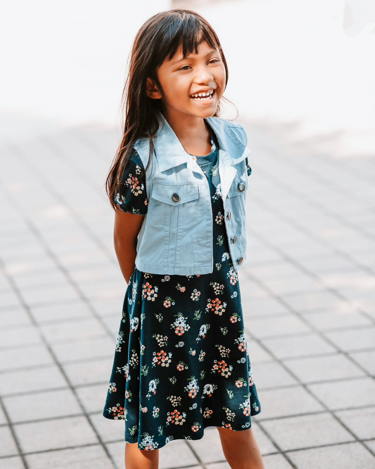 cute & little | dallas petite fashion blog | back to school outfits jcpenney | School Routine by popular Dallas motherhood blog, Cute and Little: image of a young girl standing outside and wearing a blue floral print dress and denim vest. 