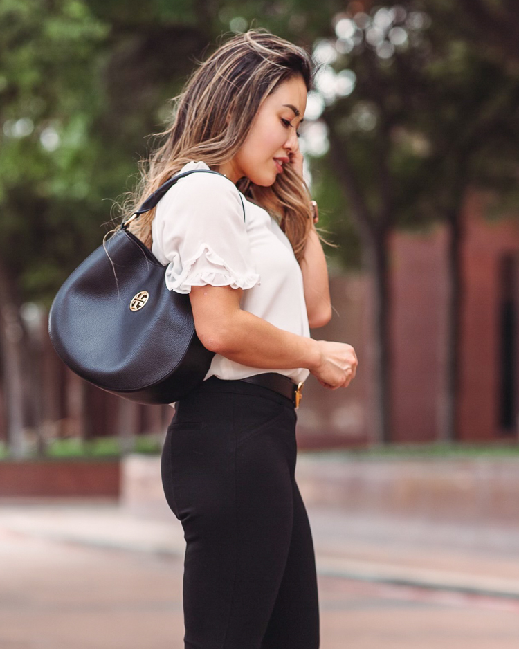  Nordstrom Anniversary Sale by popular Dallas petite fashion blog, Cute and Little: image of a woman standing in a street and wearing a Nordstrom white ruffle blouse, black Gucci belt, black Spanx pants, and Tory Burch black hand bag. 