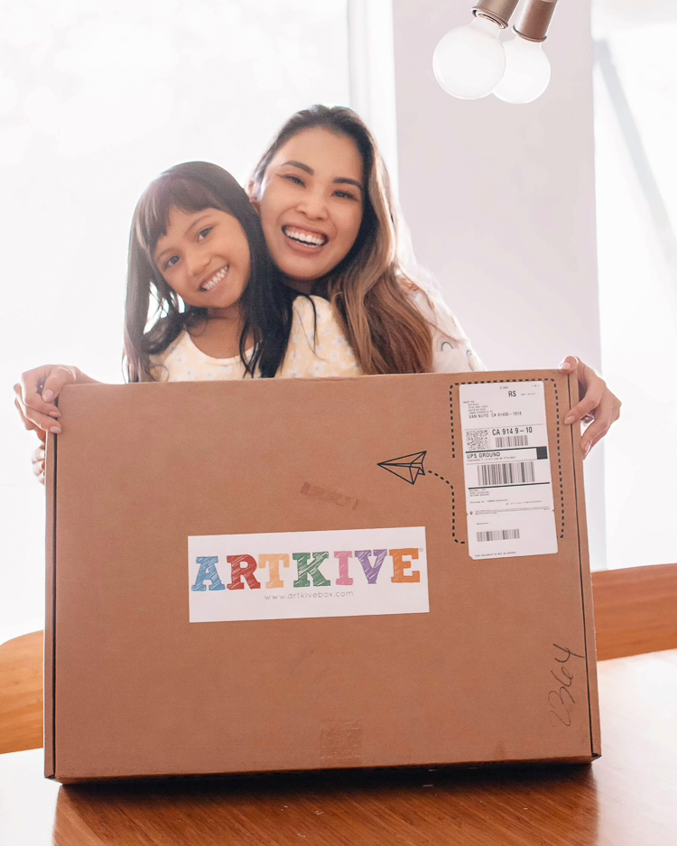 cute & little | dallas mom blogger | Artkive review | parenting de-clutter tip | how to store kids' artwork | Kids Artwork by popular Dallas motherhood blog, Cute and Little: image of a mom and her young daughter holding a Artkive box. 
